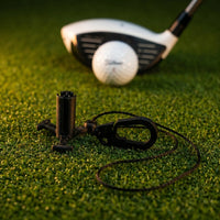 Sebo Golf Simulator Tee mit Verbindungskabel und Tee auf künstlichem Rasen.