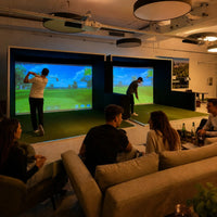 GSK ELITE Swing Dome - Golf Simulator mit zwei Bildschirmen und Spielern in einer modernen Einrichtung.